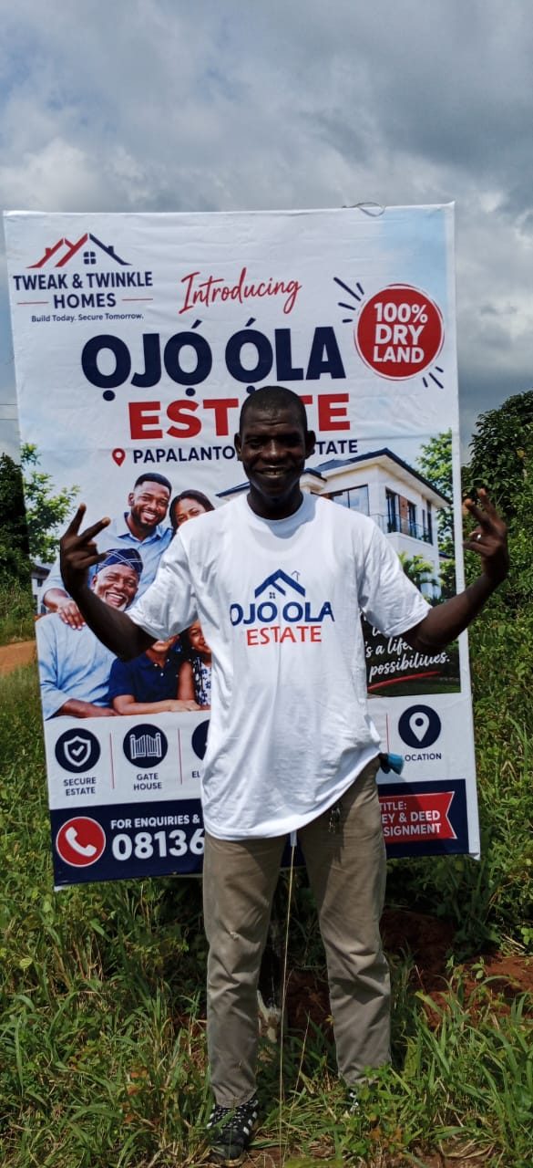 A team member in front of the Ojo-Ola Estate signboard